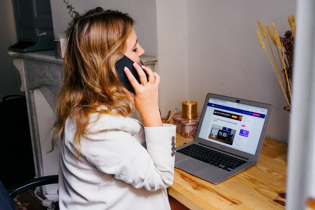 Emprendedora atendiendo una llamada frente a su computadora