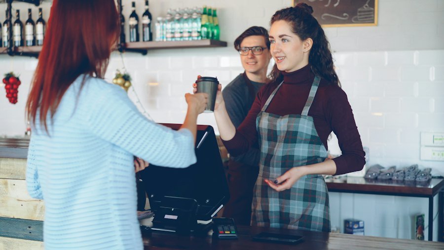 Barista atendiendo a una clienta en el mostrador de un café