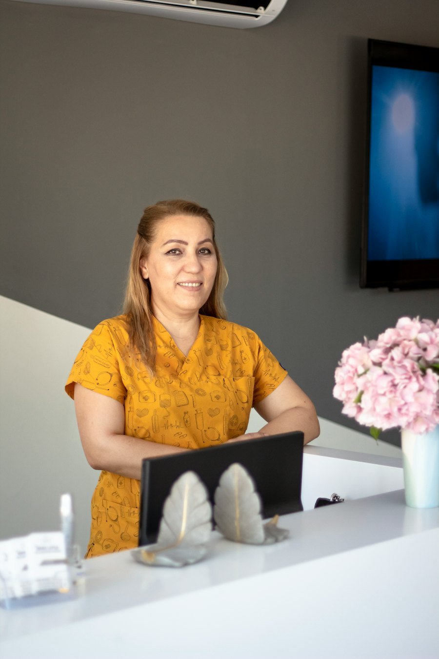 Recepcionista sonriendo en el mostrador de un consultorio
