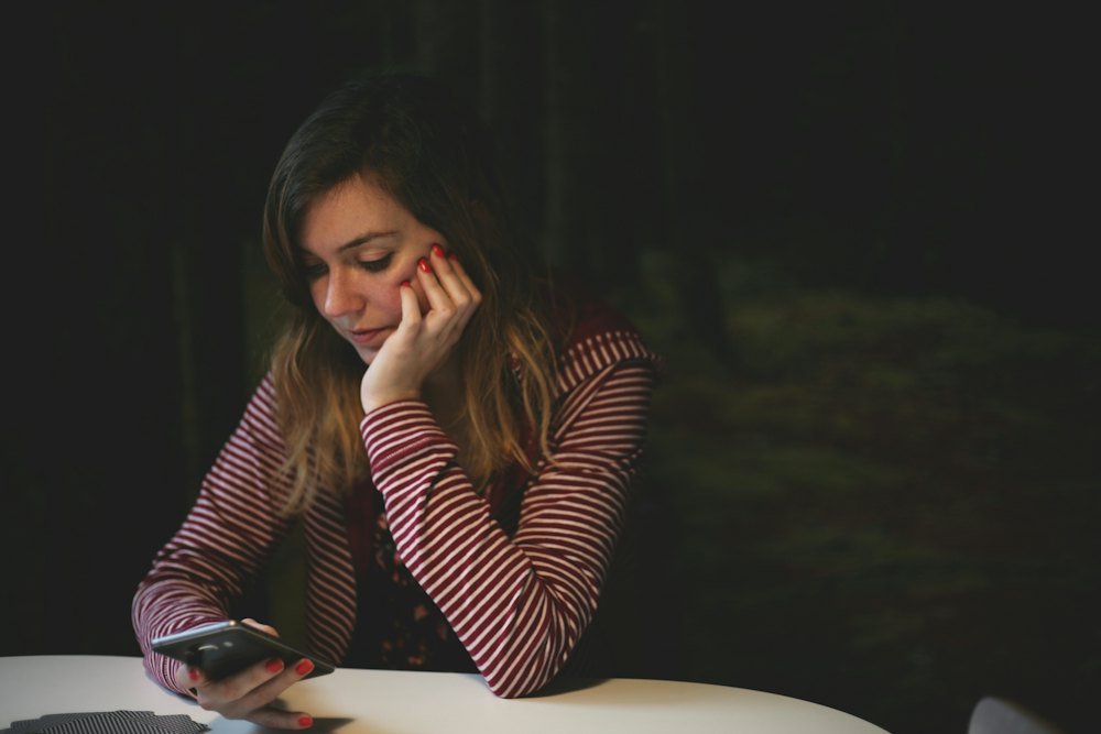 Mujer cansada revisando mensajes en su teléfono de noche
